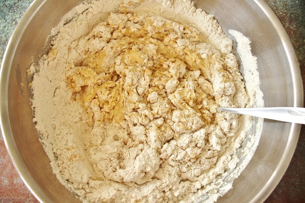 Adding the wet ingredients to the dry ingredients for chorek in a metal mixing bowl