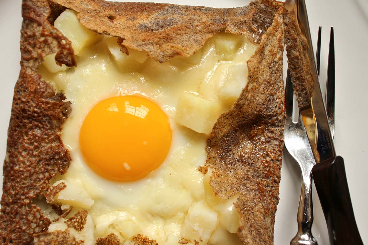 buckwheat crepe with egg and potatoes with a knife and fork on the side