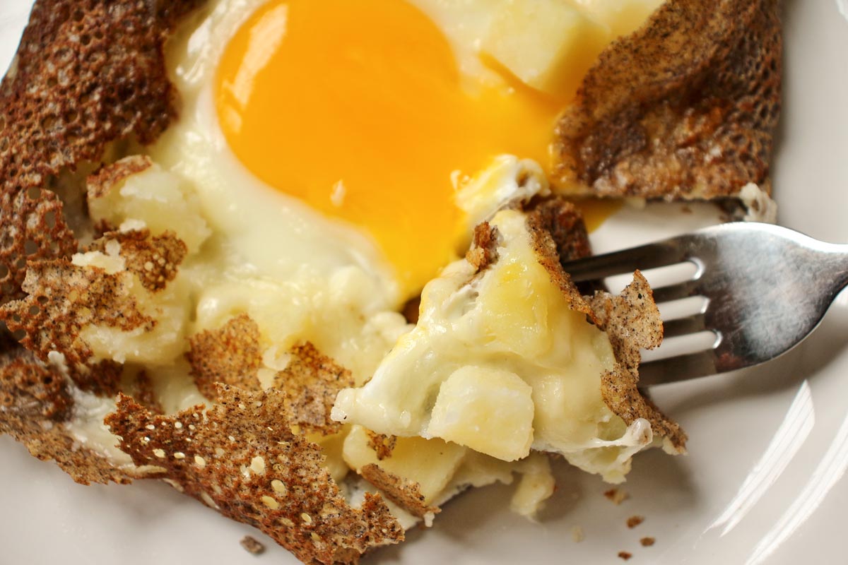 A buckwheat galette filled with potatoes, cheese, and fried egg