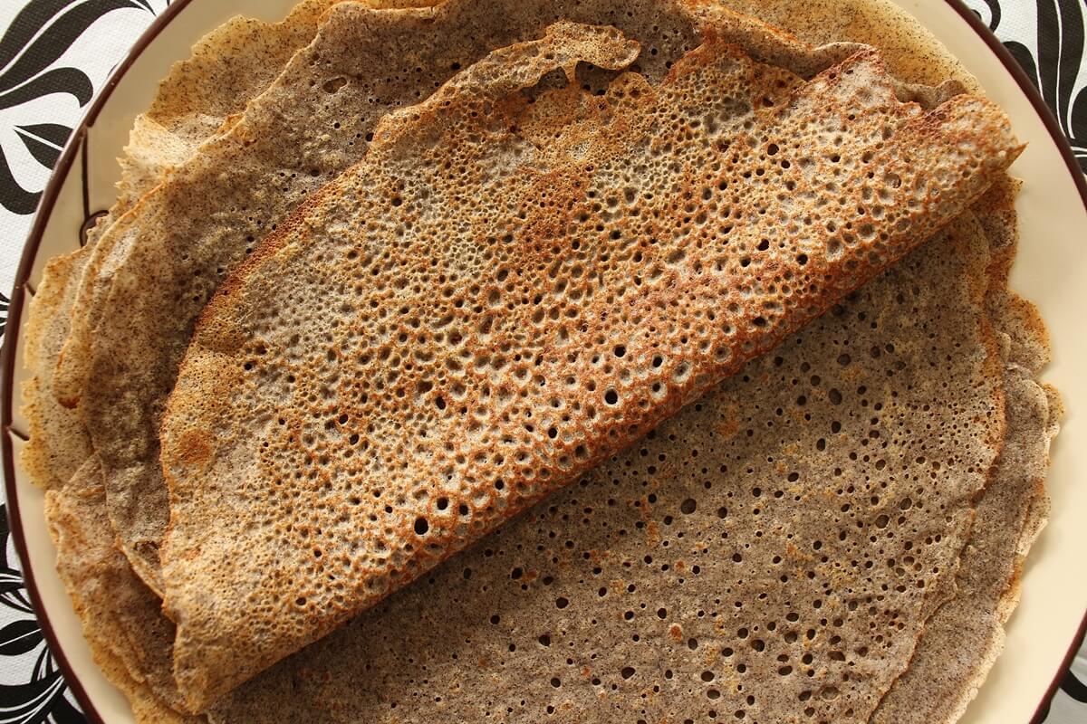 Stack of buckwheat galettes on a plate, with one folded over