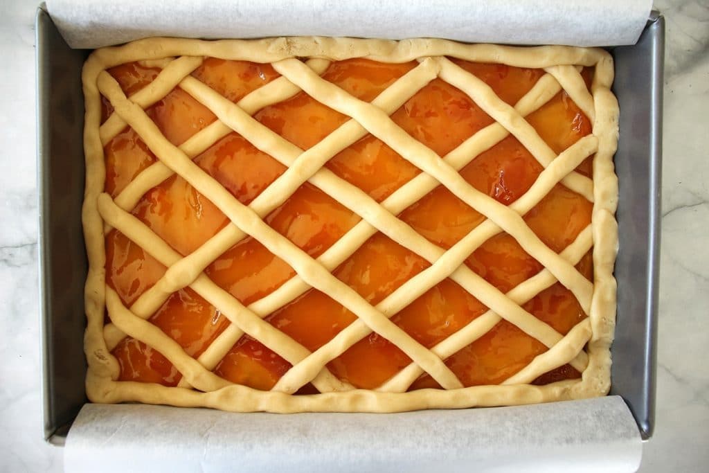 The finished Russian pirog before baking, with a lattice top and apricot jam peeking through