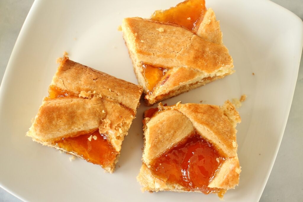 Overhead view of 3 squares of apricot filled Russian pirog on a white plate
