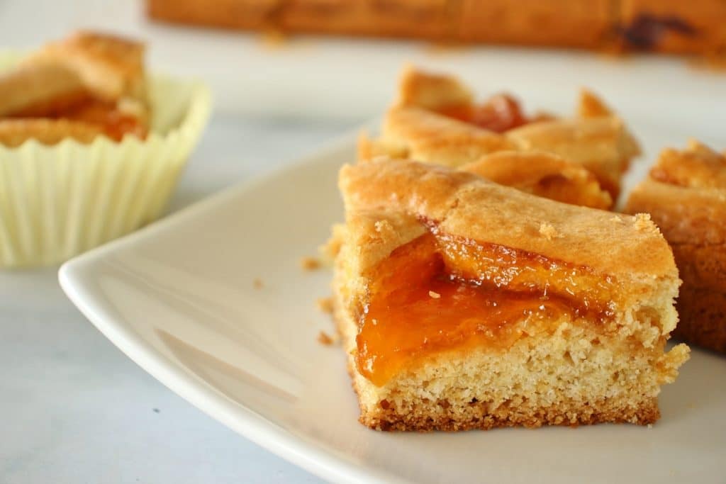 A closeup of 3 squares of apricot filled Russian pastry on a white plate