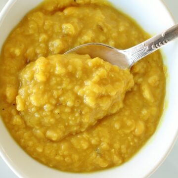 a bowl of yellow chana dal curry with a spoon