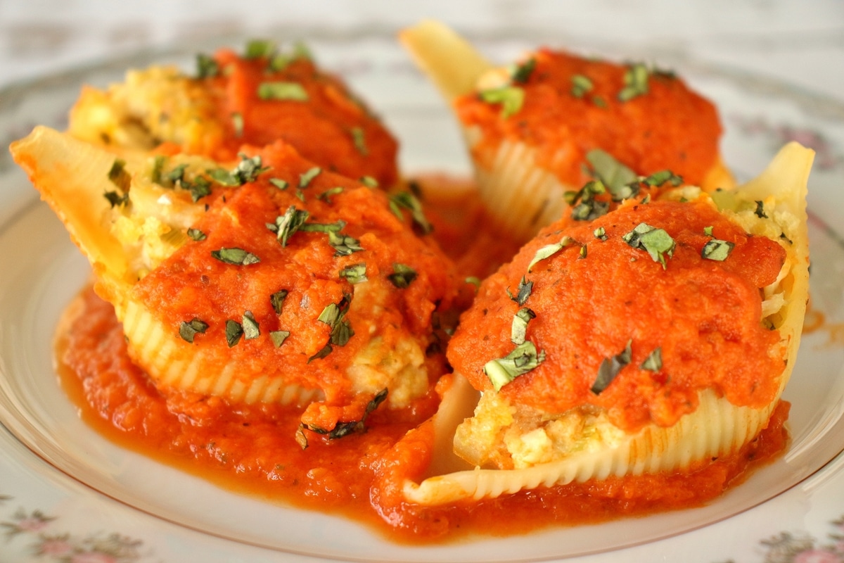 Four crab stuffed shells topped with orange-infused tomato sauce and chopped basil