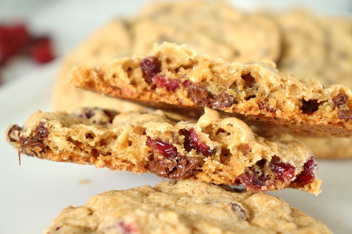 Closeup of a cookie broken in two pieces to show chocolate chips and dried cranberries inside.