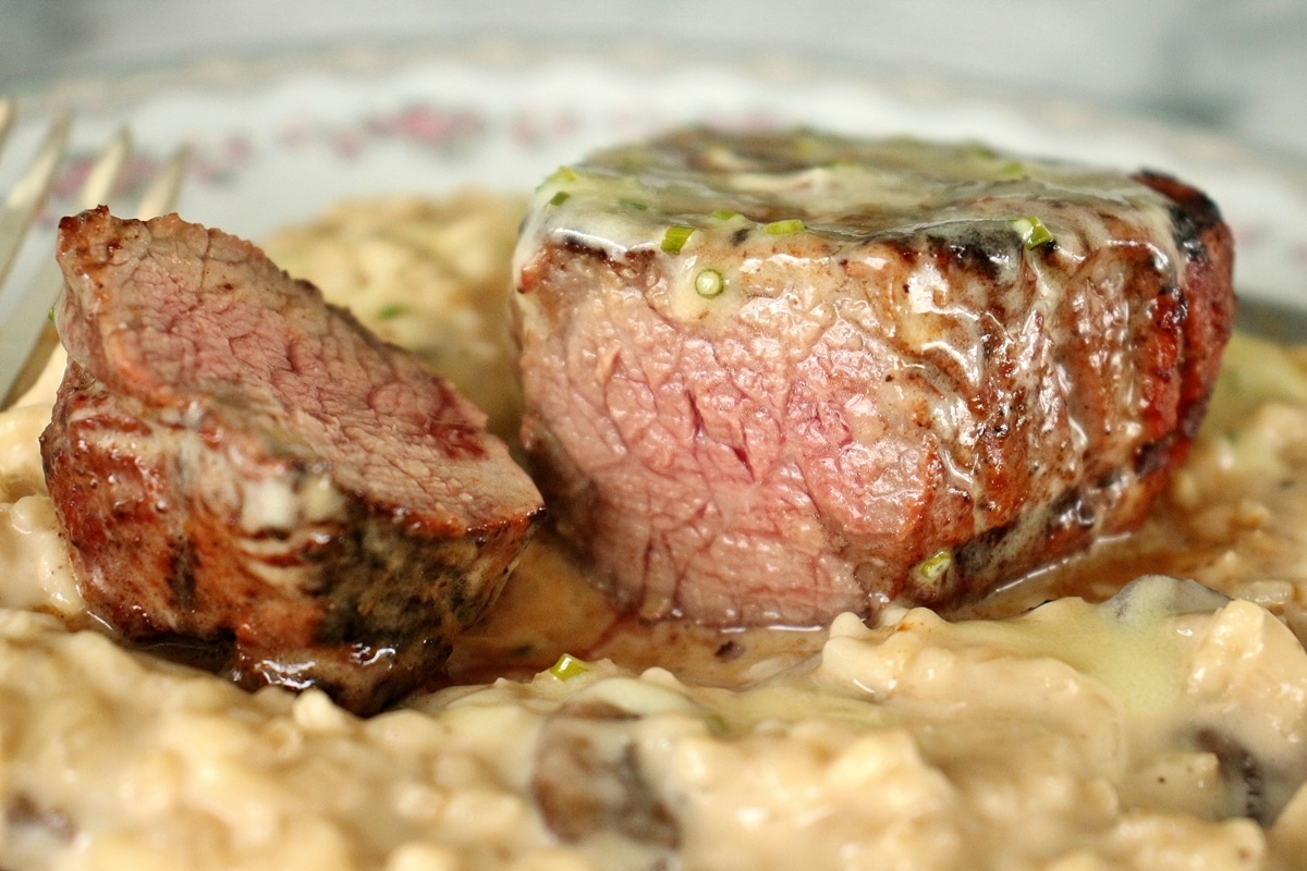 Closeup of a sliced filet mignon steak over a bed of mushroom risotto