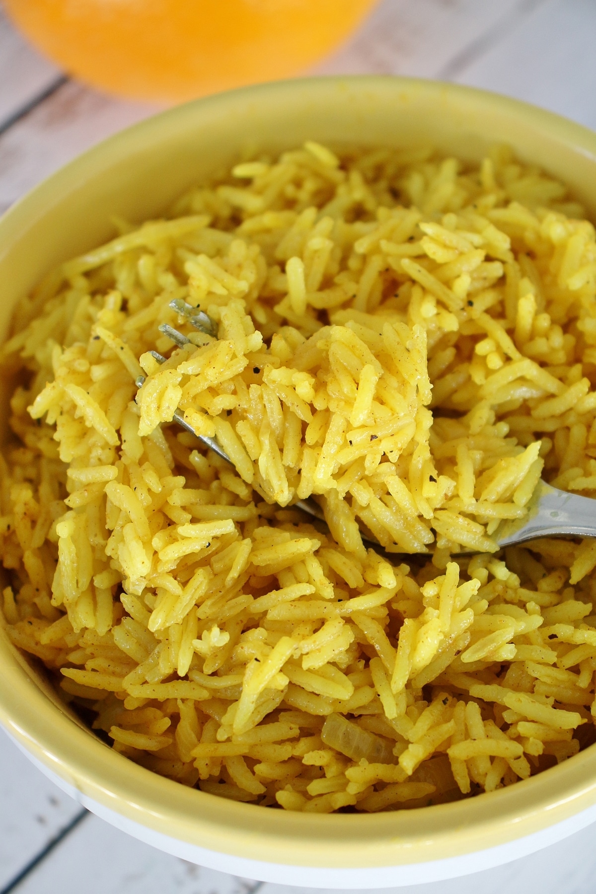 A bowl of Caribbean curried citrus rice with a fork scooping some up