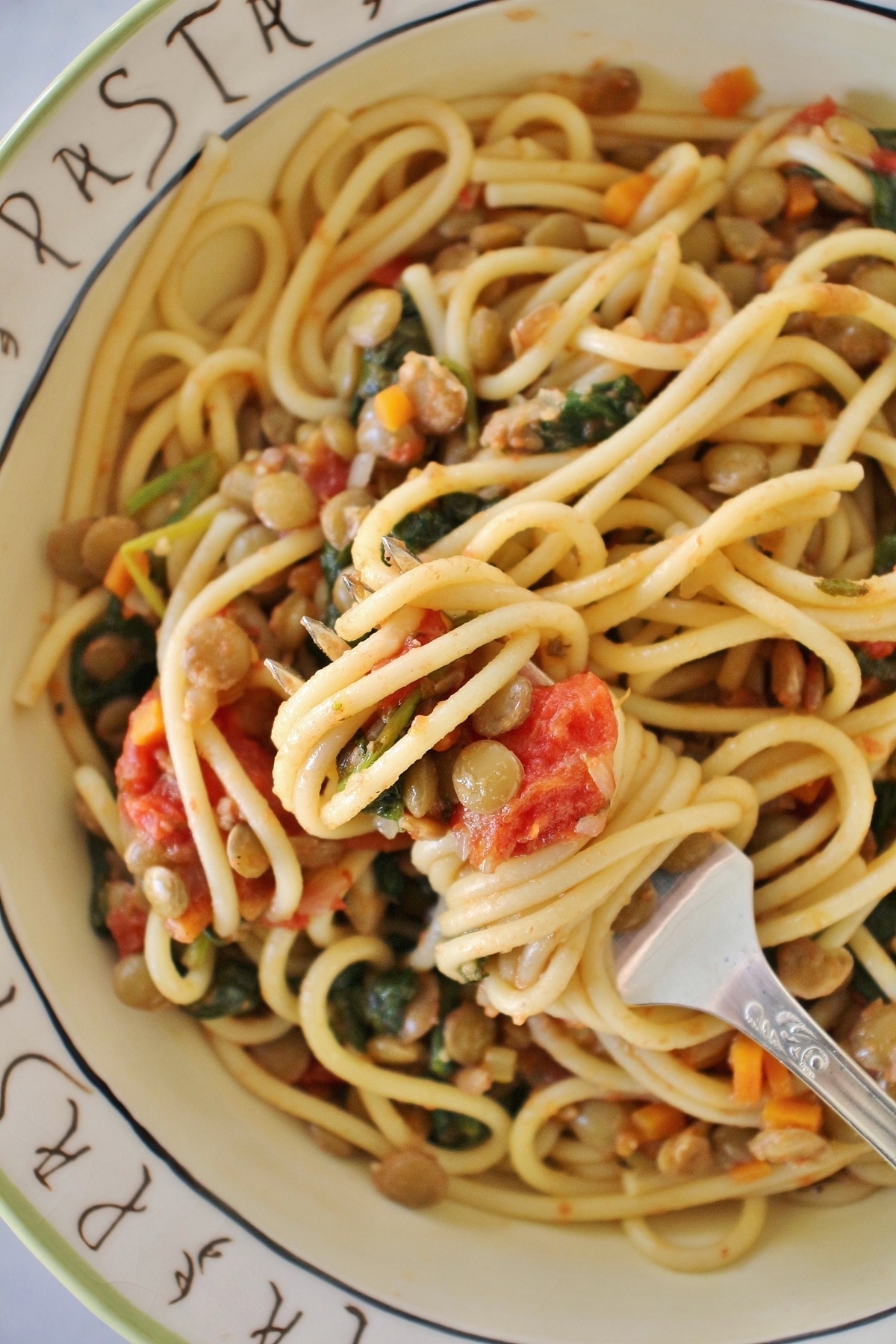 spaghetti with lentils, roasted tomatoes, and spinach twisted around a fork