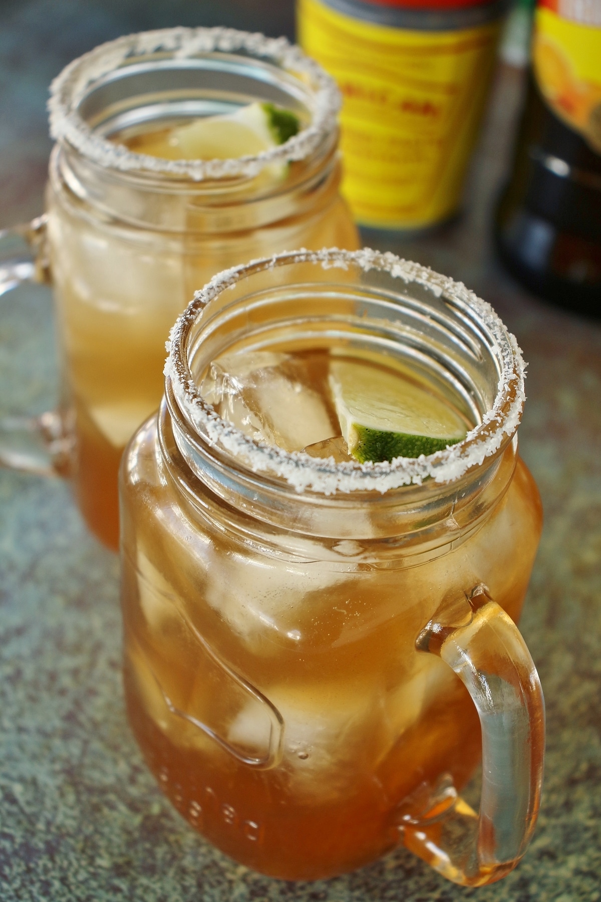 2 tamarind margaritas with salt rims and lime wedge garnish, served in mason jar mugs