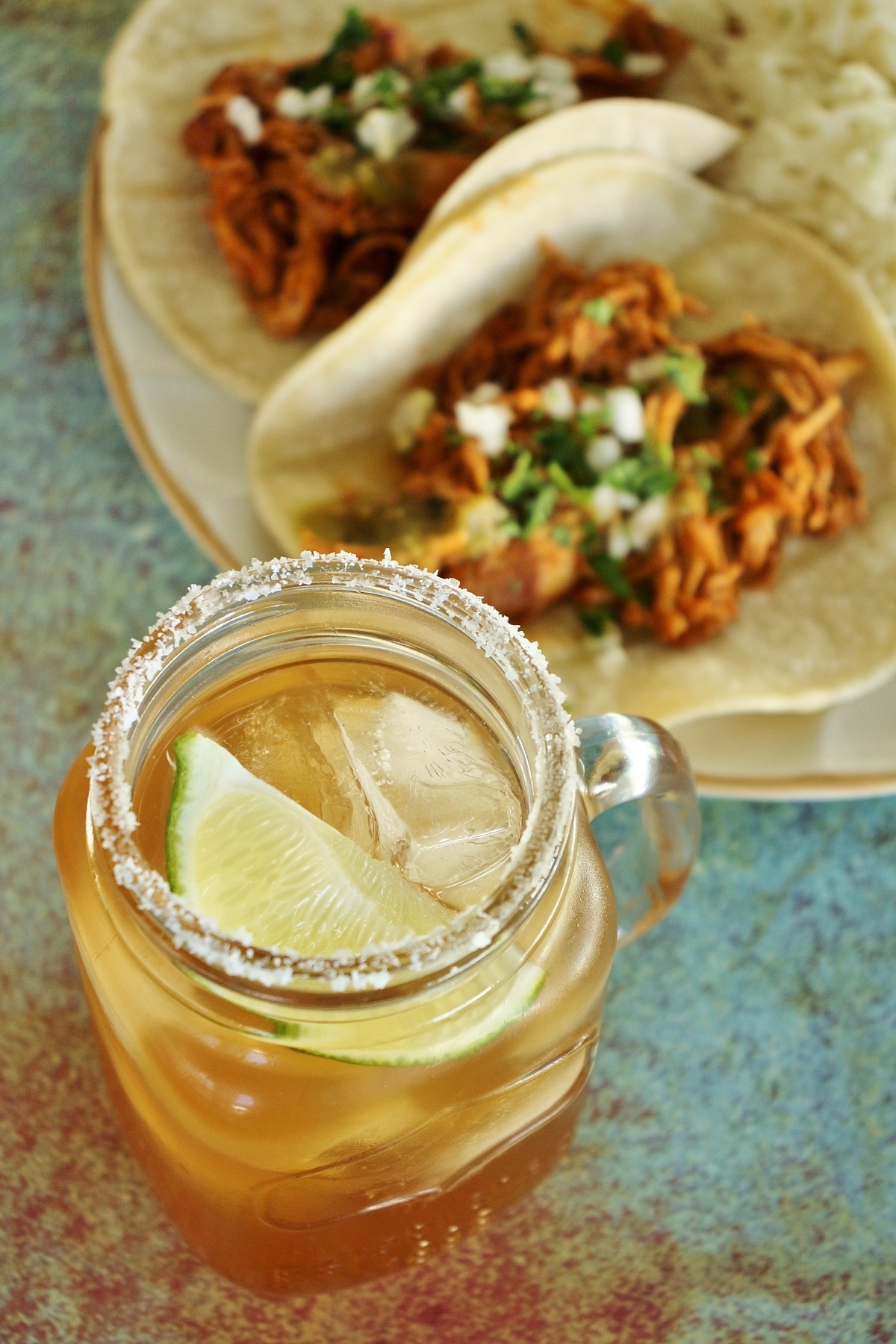 tamarind margarita in mason jar mug, with tacos in the background