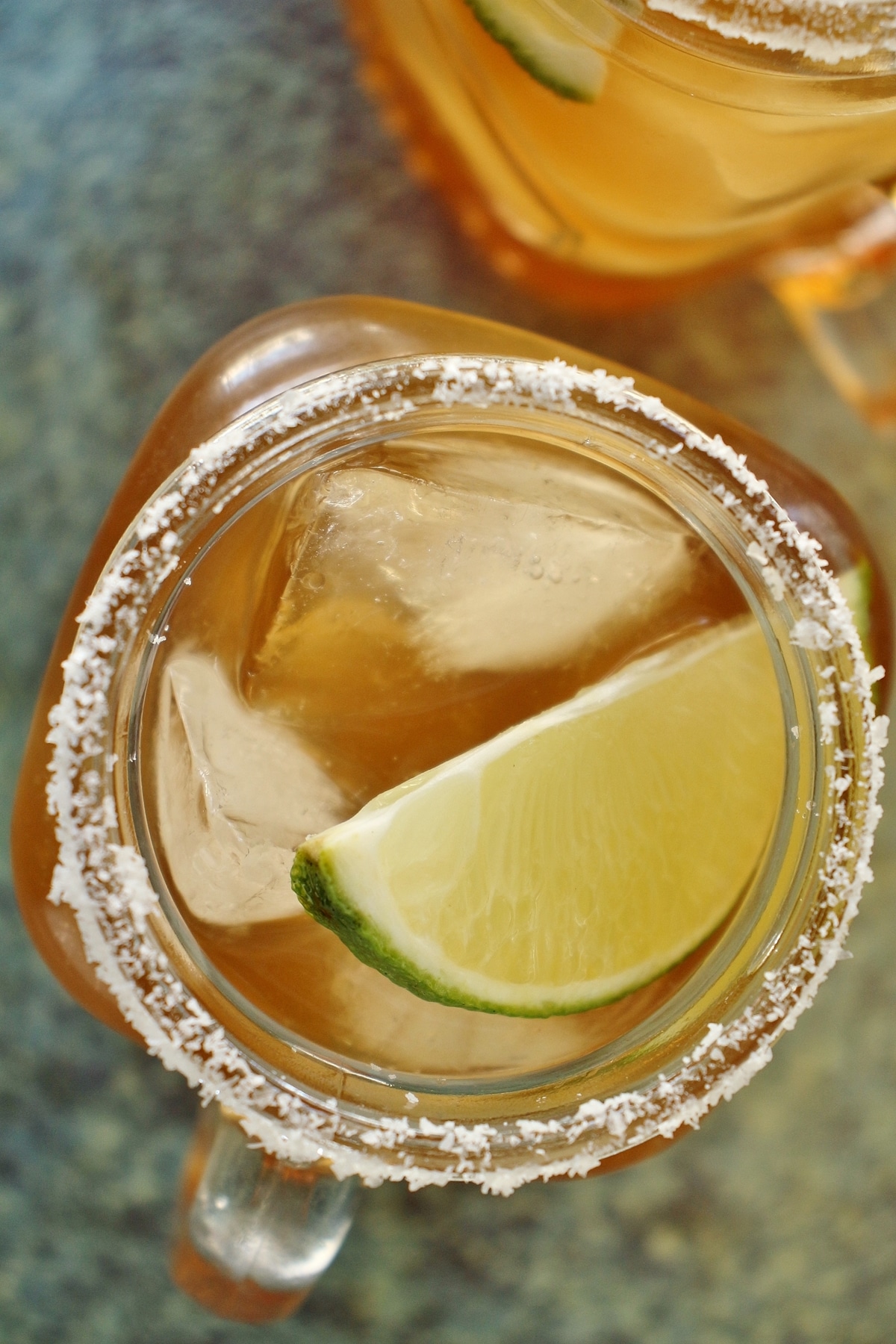 Overhead closeup view of 2 tamarind margaritas with salt rims and lime