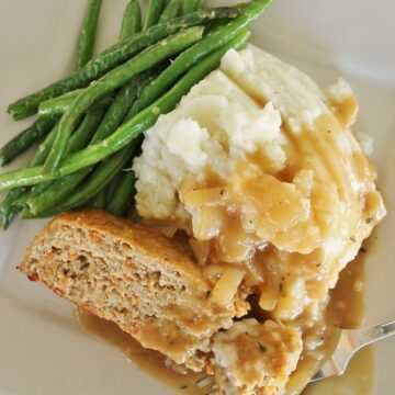 turkey meatloaf with onion gravy, mashed potatoes, and green beans on a square plate
