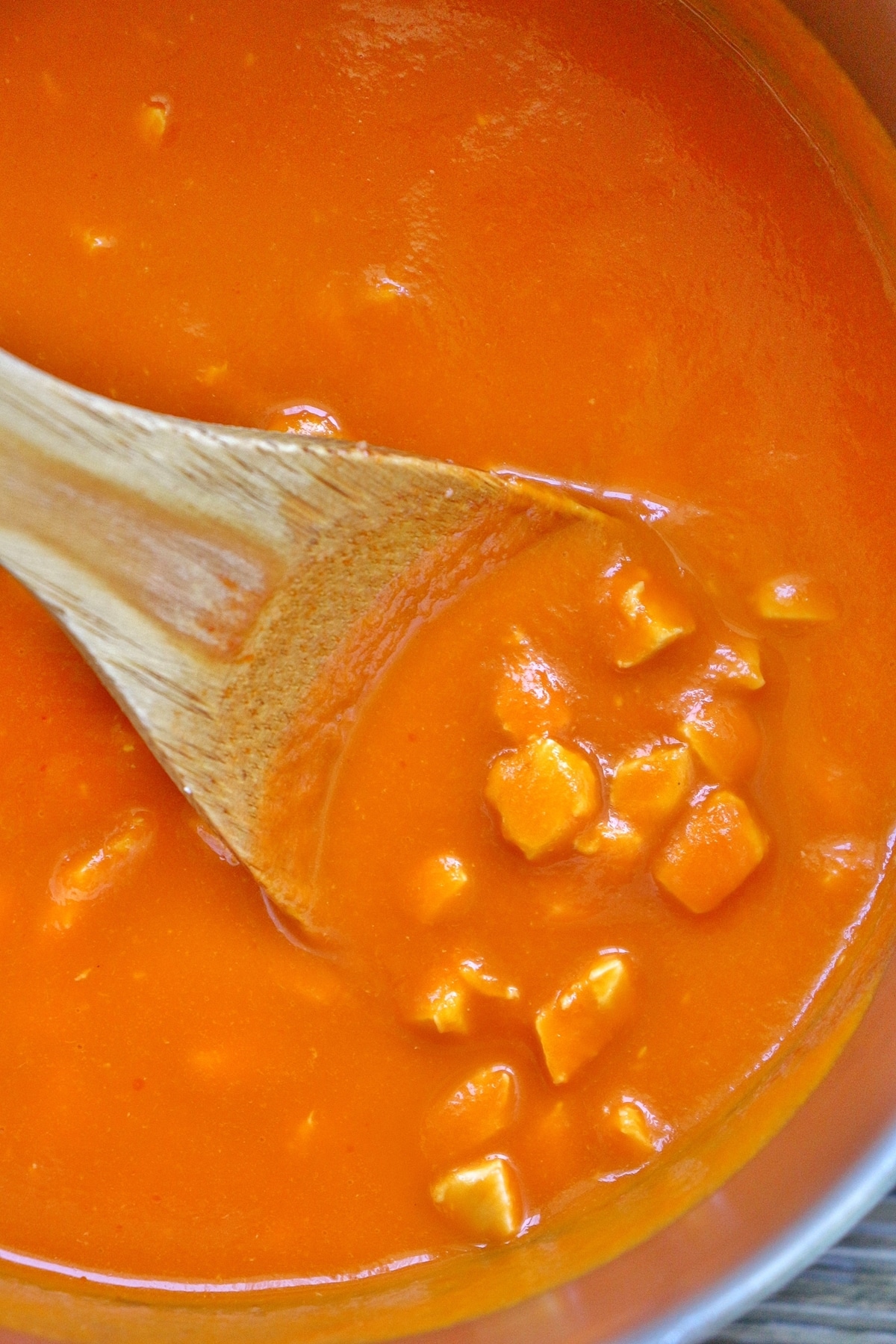 Bite-size pieces of chicken in an orange-colored pasta sauce in a saucepan