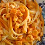 fettuccine with orange-hued Venetian chicken sauce in a shallow blue and white bowl