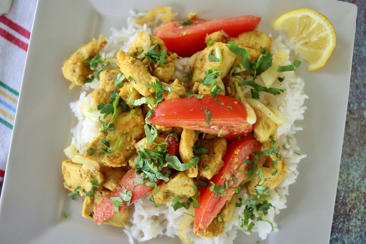 Burmese chicken kebat stir-fry with cilantro and tomatoes on a square plate