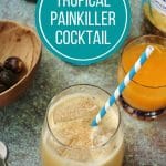 a tropical painkiller cocktail with a blue striped paper straw and ingredients in the background