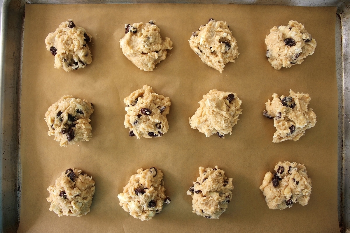 Dough for rock cakes scooped out into 12 mounds on a parchment paper-lined baking sheet