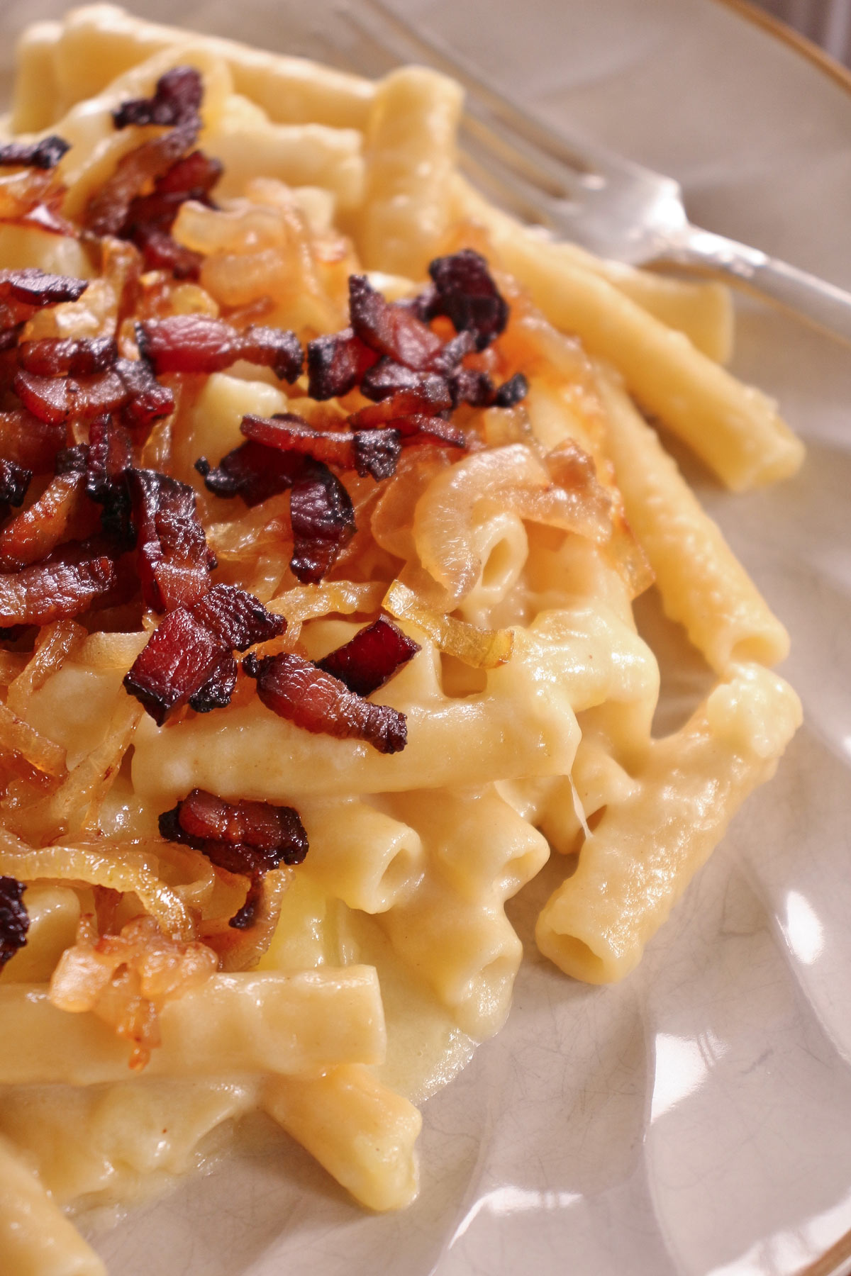 Closeup of Swiss mac and cheese made with ziti, topped with bacon pieces.