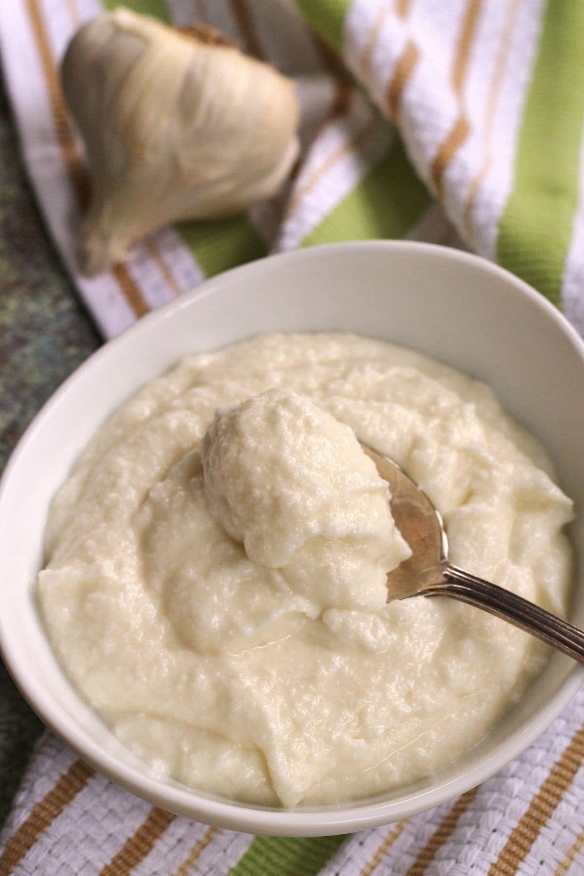 closeup of creamy white Zankou Chicken garlic sauce in a white bowl with a spoon