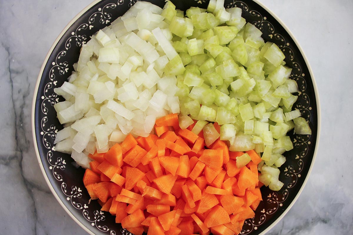 Diced onion, celery, and carrot in a bowl.