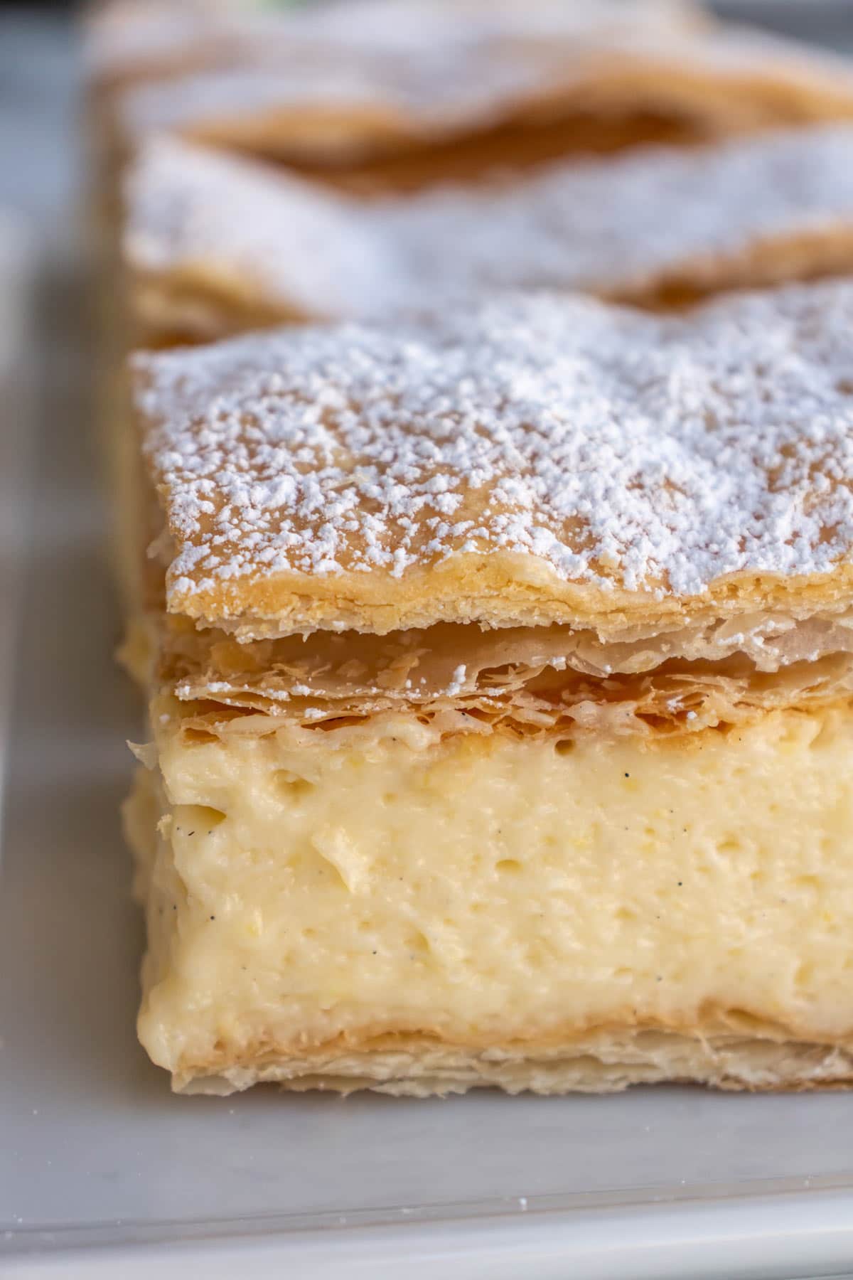 Closeup of a row of Austrian cream slices (cremeschnitte) on a white plate.
