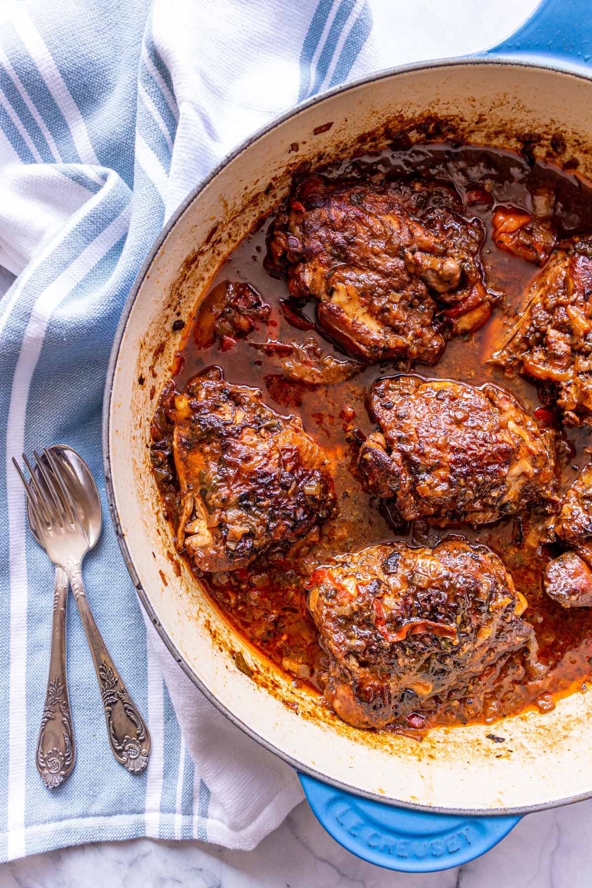 Brown stew chicken thighs in a blue enameled cast iron saute pan.