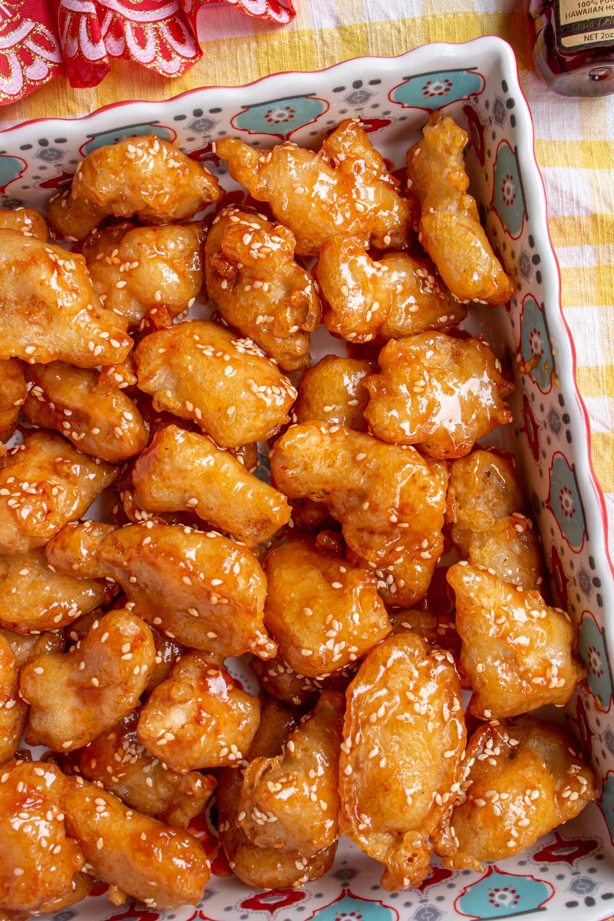 Closeup of fried honey sesame chicken in a square serving dish.