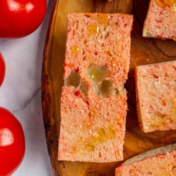Closeup of Spanish tomato bread drizzled with olive oil on a wooden board.