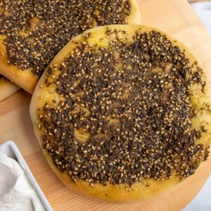 Closeup of two round loaves of za'atar manakish flatbread on a wooden board.