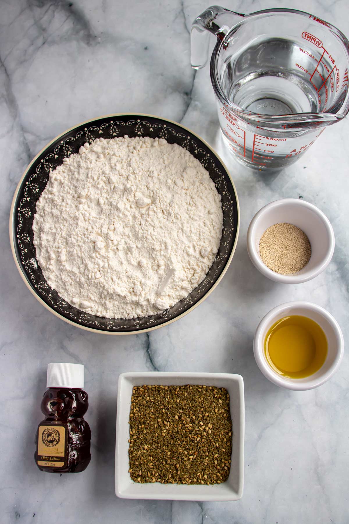 Ingredients for za'atar bread on a white marble background.