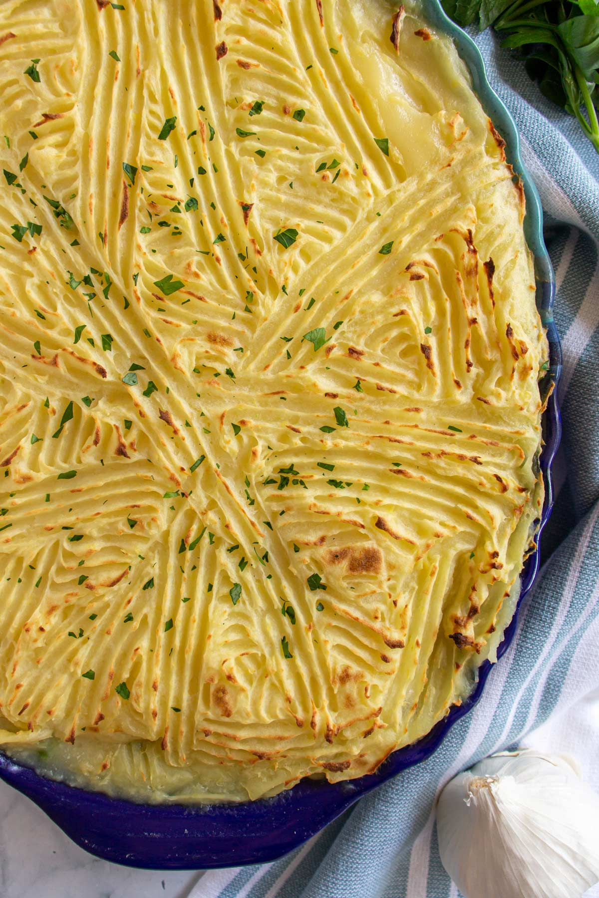 Closeup of a mashed potato crust with ridges on top of an oval baking dish.