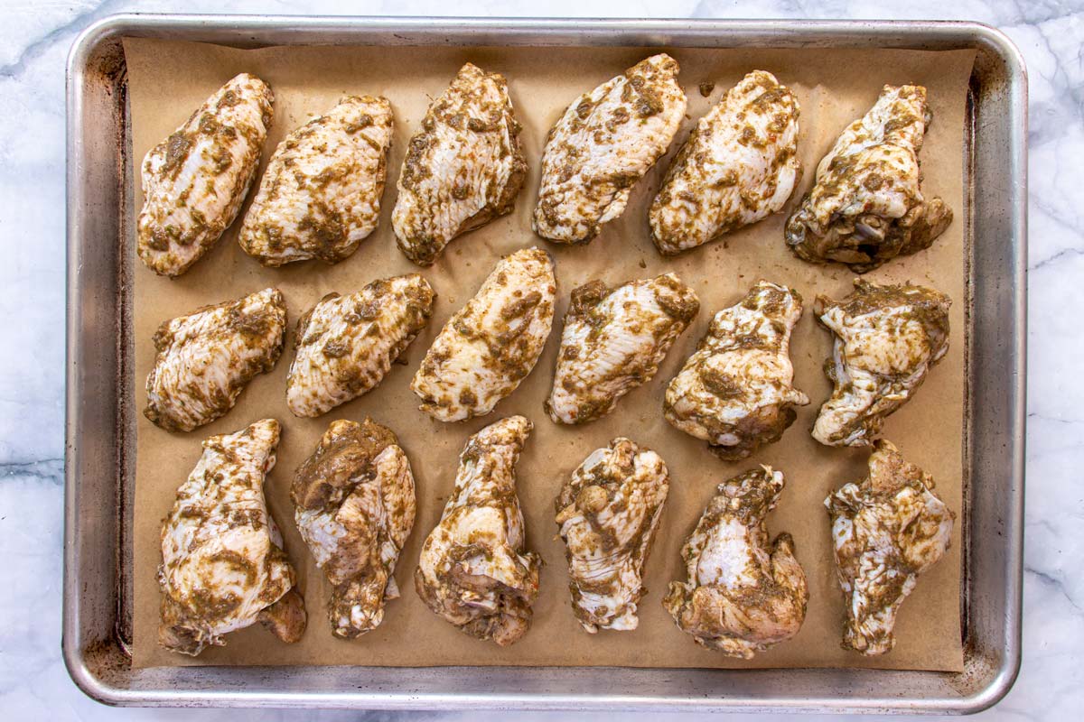 Unbaked chicken wings on a parchment paper lined baking sheet.