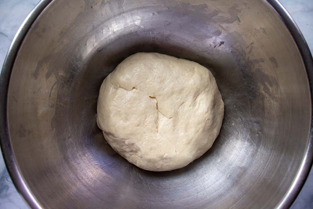A ball of dough in a metal mixing bowl.