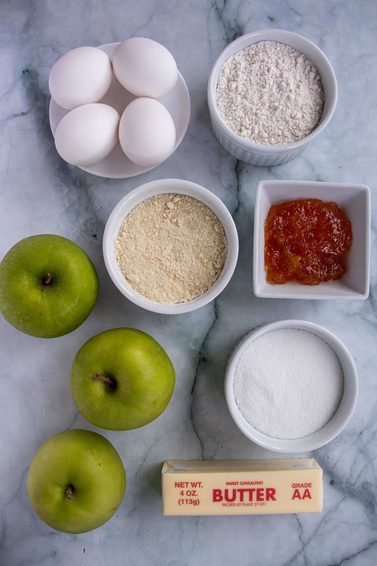 Ingredients for tarte aux pommes on a white marble background.