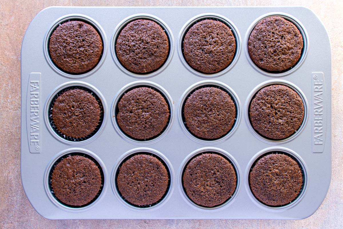 Baked chocolate cupcakes in a metal muffin pan.