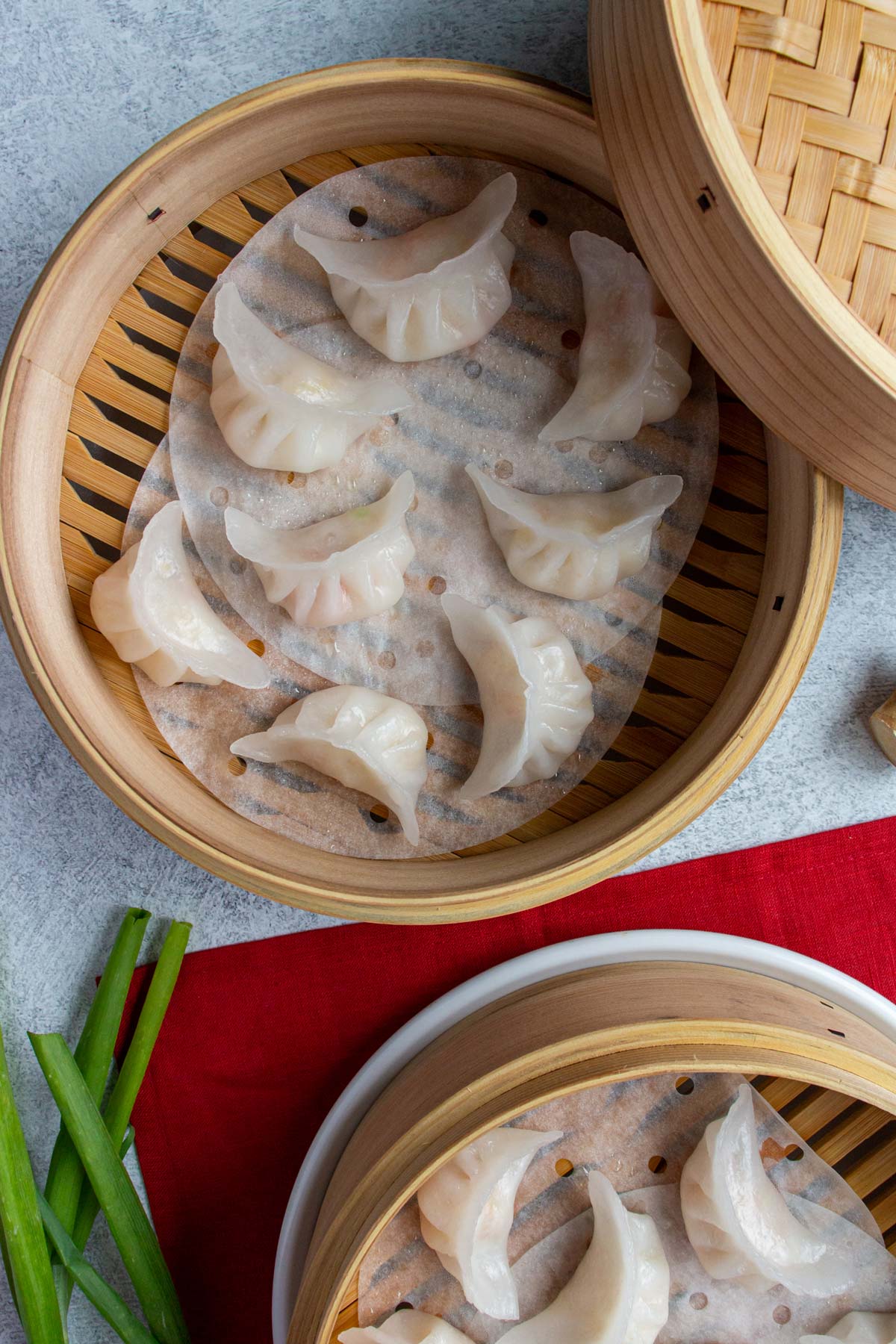 Two bamboo steamer baskets filled with steamed dumplings with white translucent wrappers.