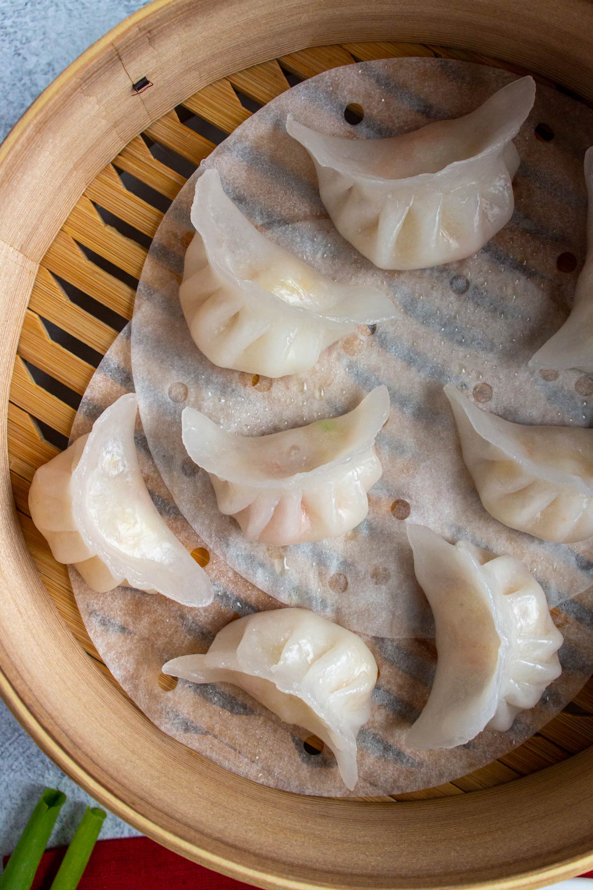 Translucent white crystal shrimp dumplings with crescent shapes in a bamboo steamer basket.