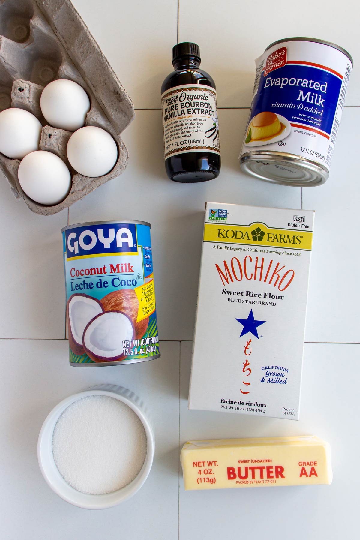 Ingredients for Hawaiian butter mochi on a white tile background.