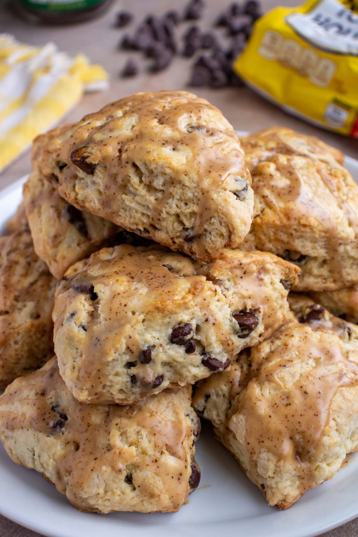 Chocolate chip scones with espresso glaze piled on top of each other on a white plate.