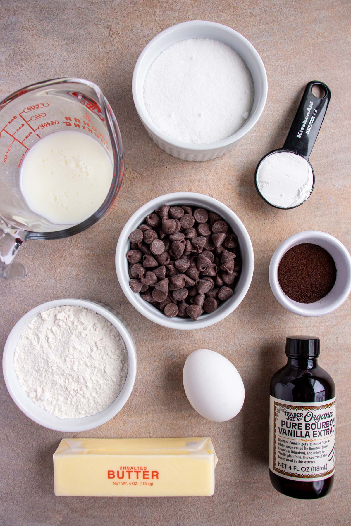 Ingredients for chocolate chip scones with espresso glaze on a tan background.
