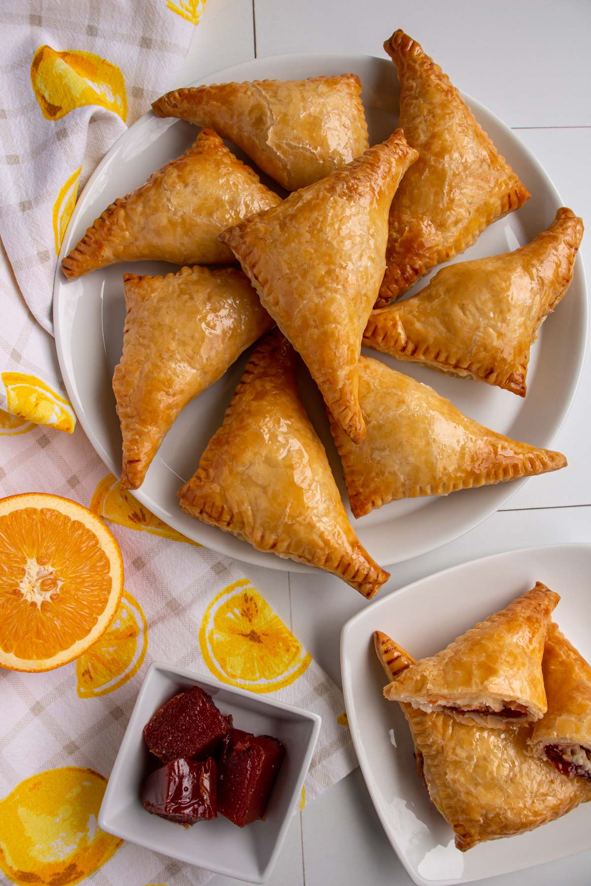 A platter of guava and cheese pastries, an orange half and a dish of guava paste.