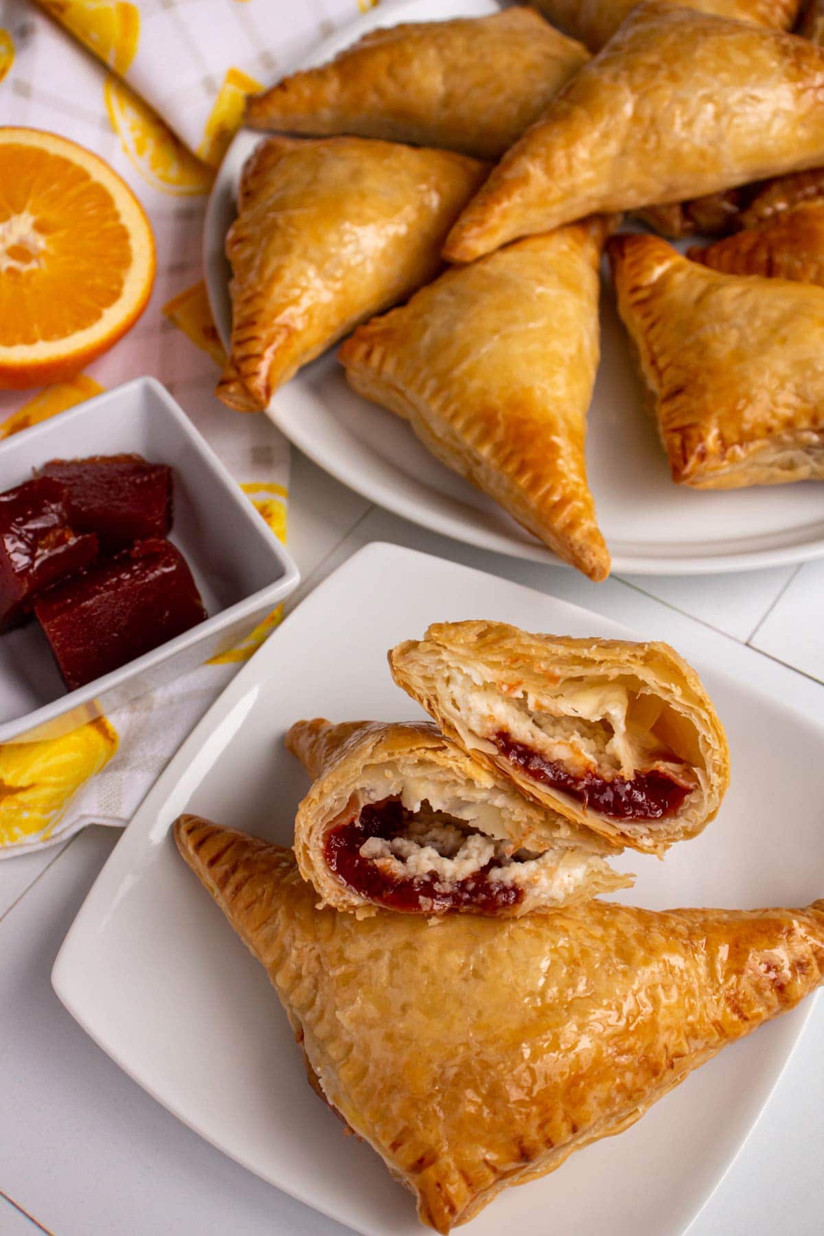 Two guava and cheese pastries with one cut in half with more pastries in the background.