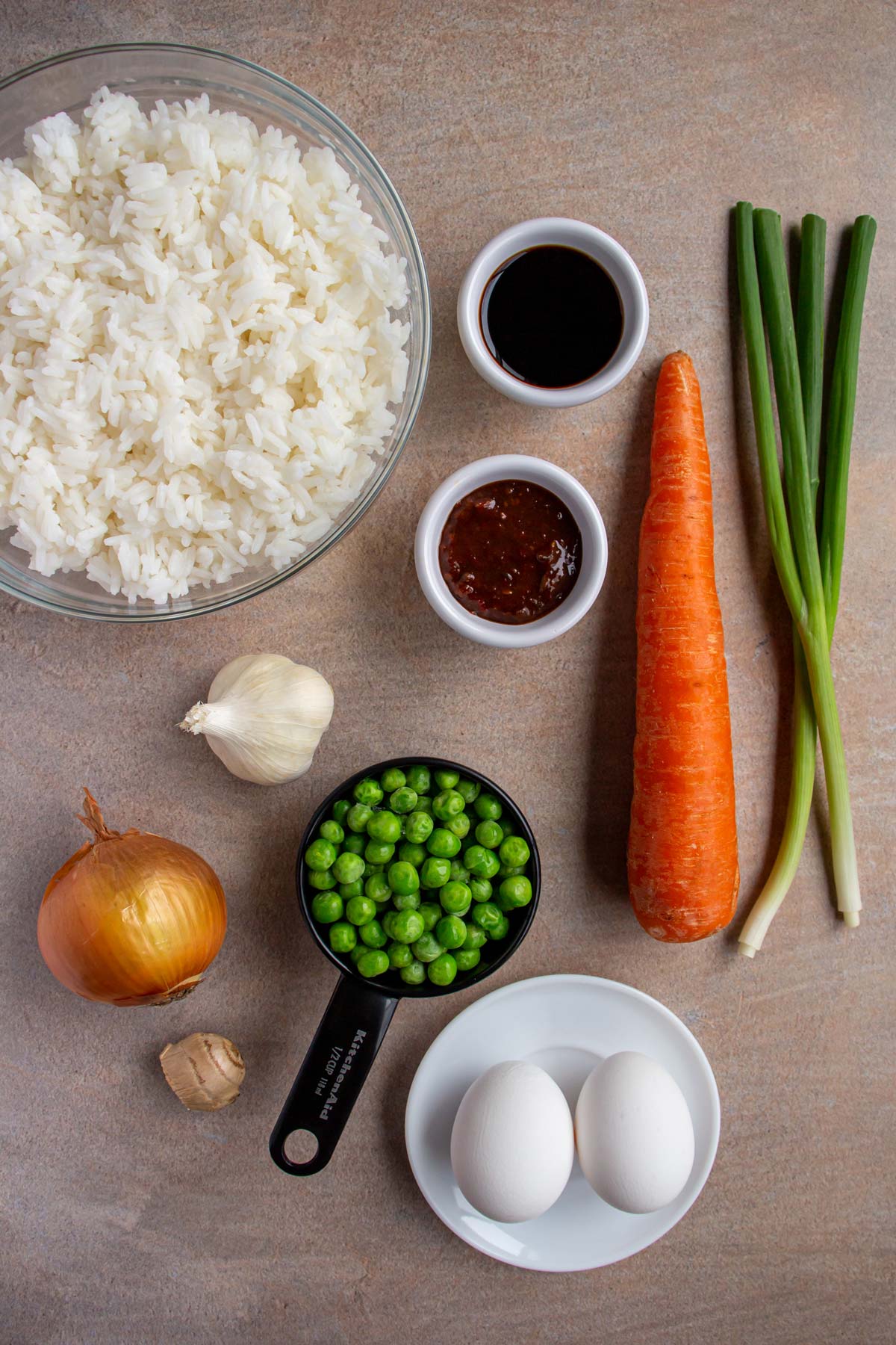 Ingredients for spicy vegetable fried rice on a tan background.