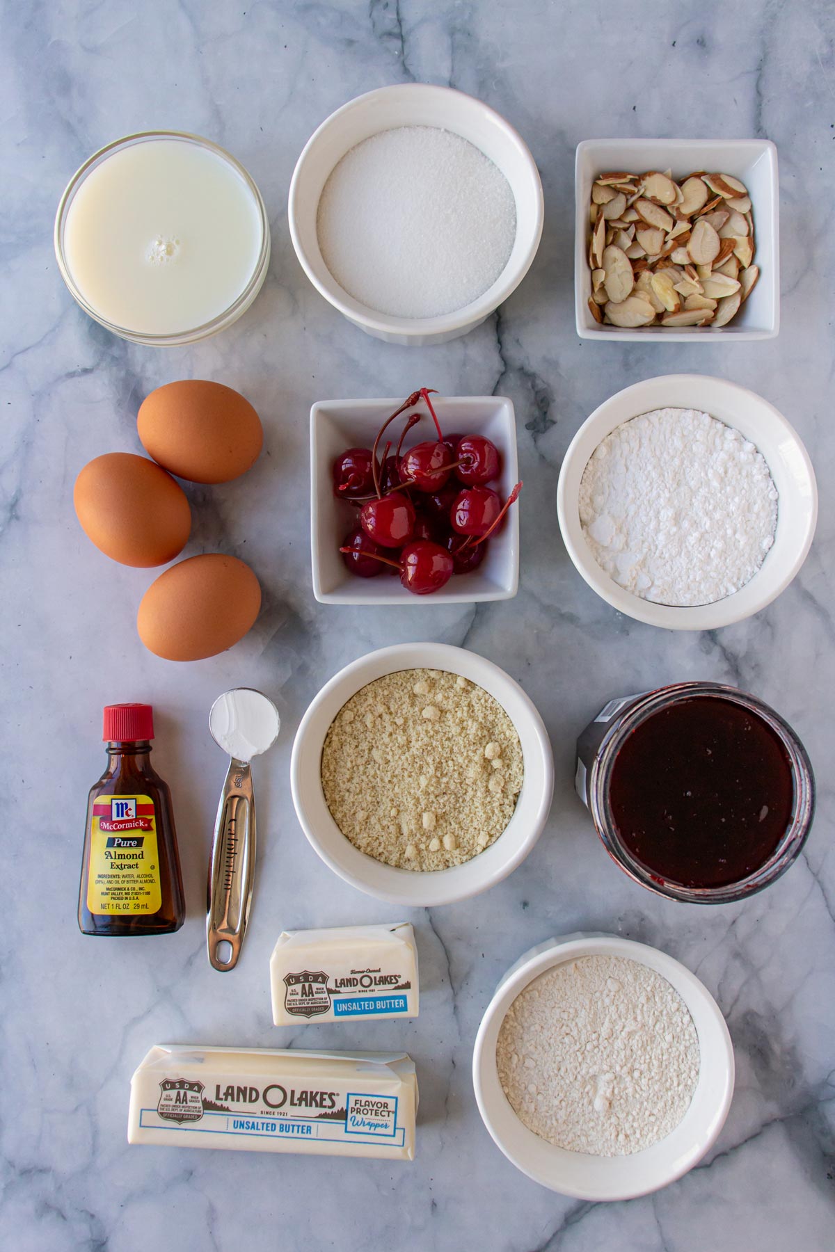 Ingredients for cherry Bakewell cake on a white marble background.