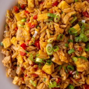 Closeup of Peruvian fried rice with chicken and vegetables topped with sliced scallions.