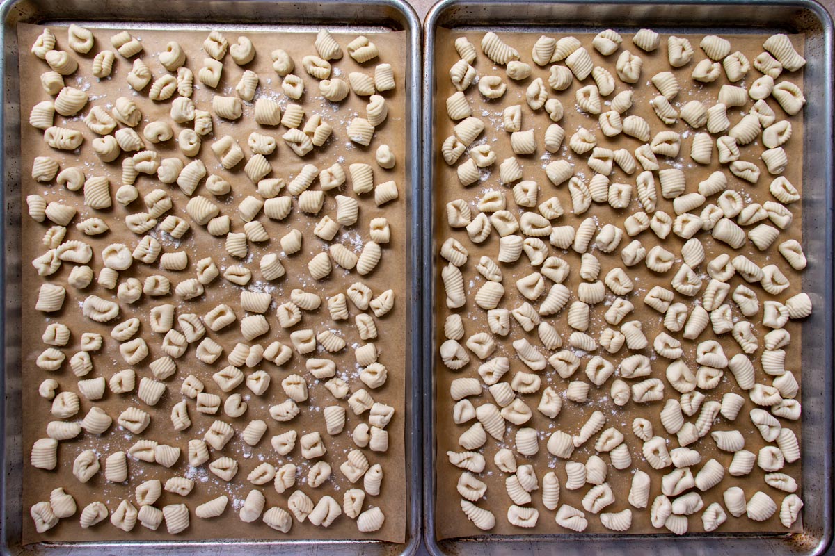 Two parchment paper lined sheet pans covered with small gnocchi with ridges.