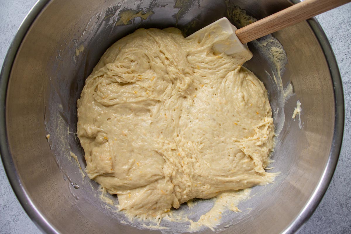 Bread batter in a metal mixing bowl with a rubber spatula.