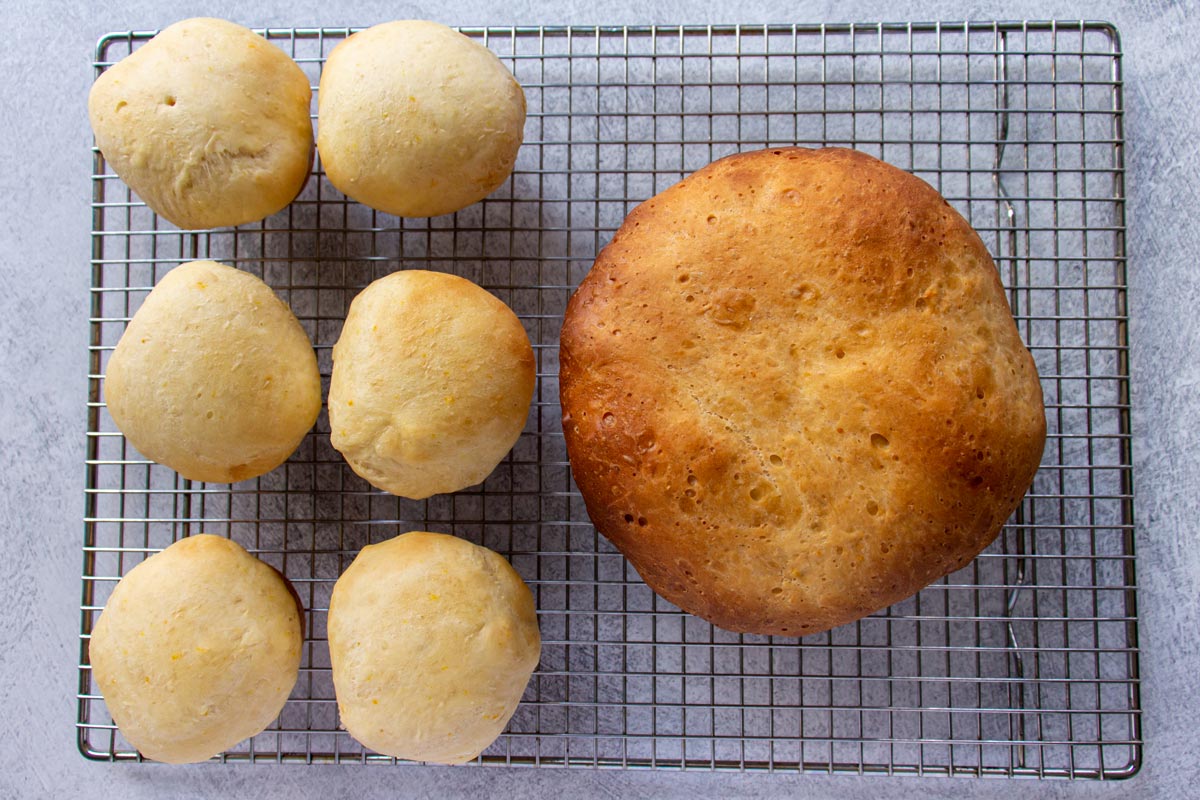 Six Sally Lunn tea buns and a large bun cooling on a wire rack.