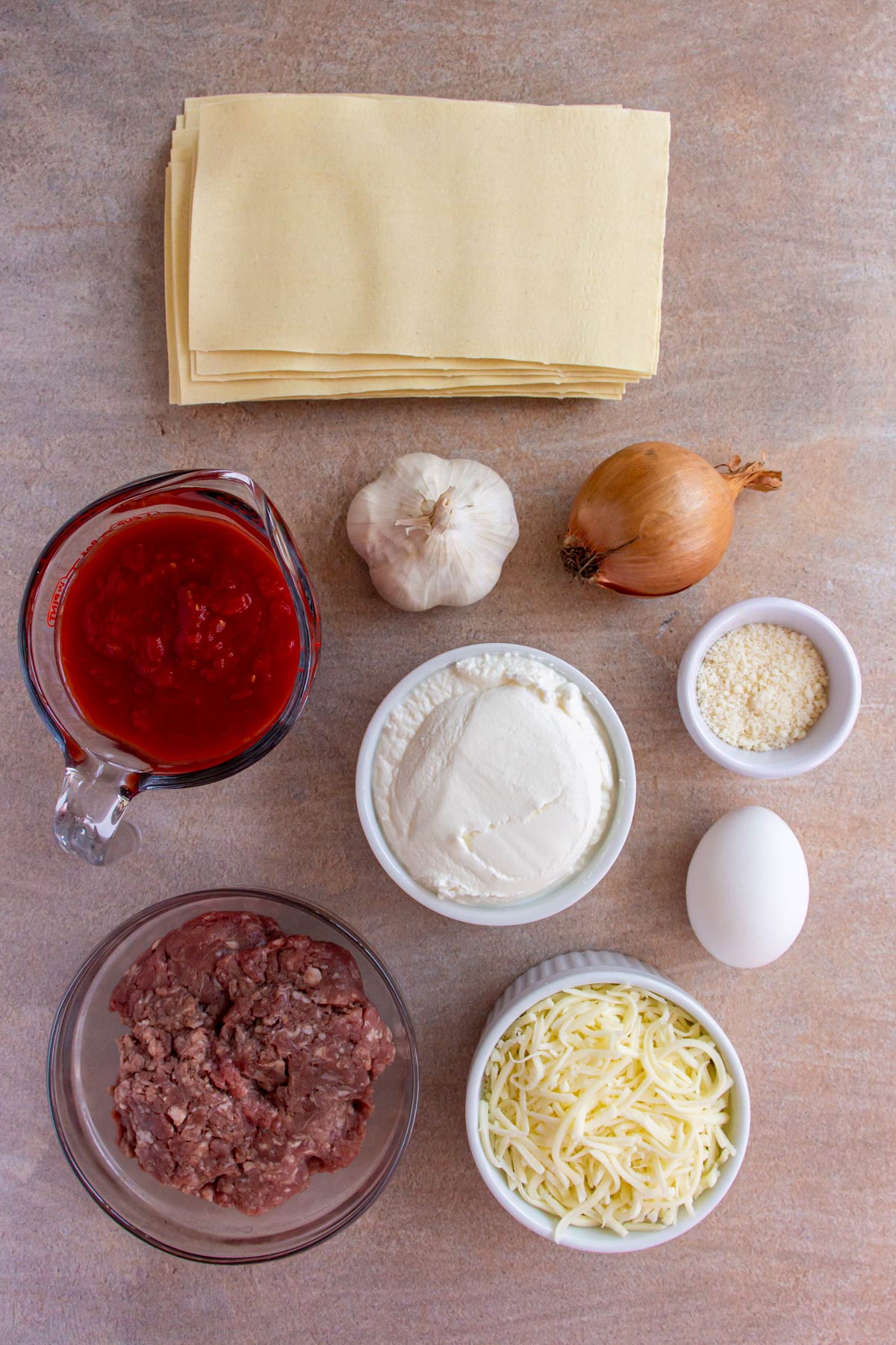 Ingredients for loaf pan lasagna on a beige background.